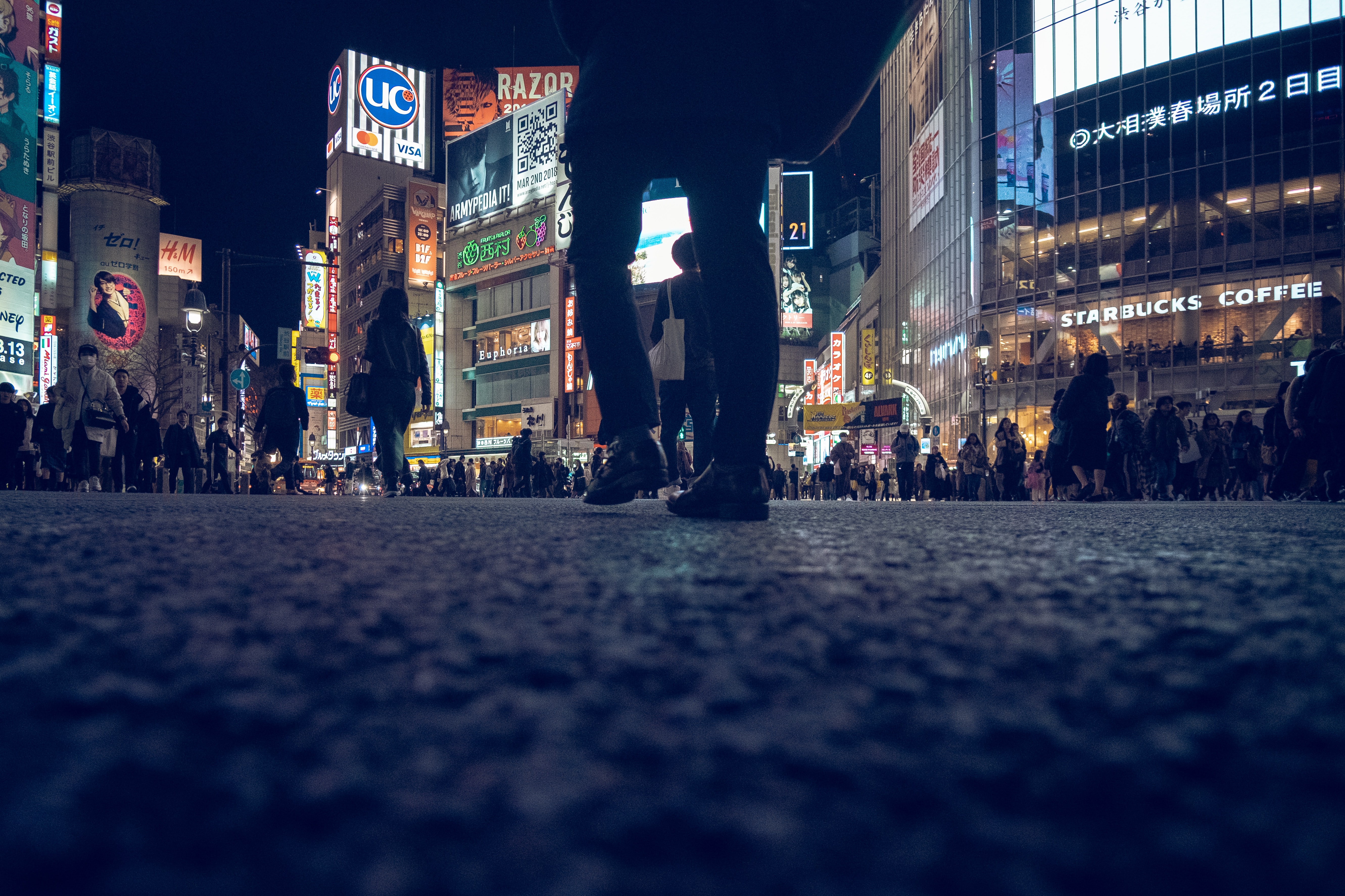 Füßgänger in einer belebten Stadt voller beleuchteter Werbetafeln bei Nacht